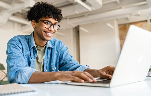 Large Young Man Smiling Typing On Laptop