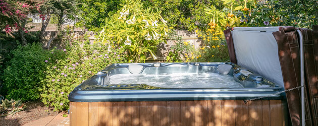 hot tub with cover in lush backyard medium