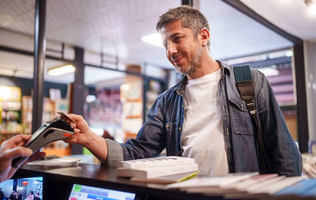 Large Male Customer Paying With Credit Card In Store