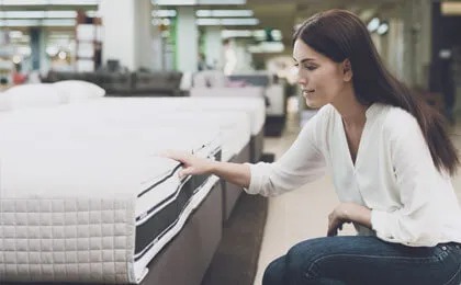 woman examines mattress in store