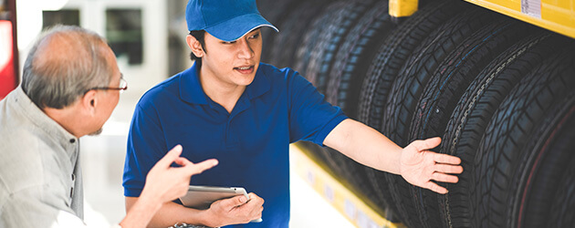 Medium Salesman Talking And Helping Customer In Tire Store
