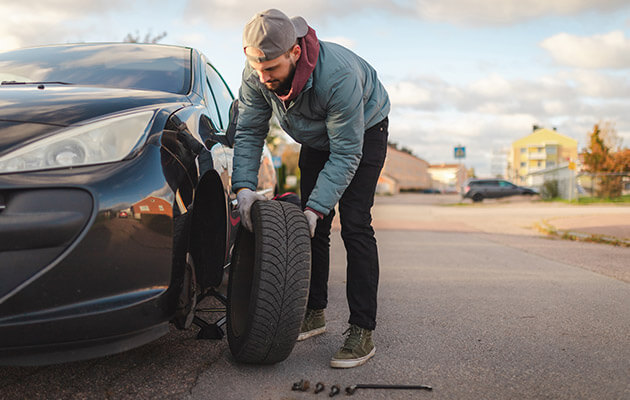 Large Men Fixing And Replacing Car Tire On The Road