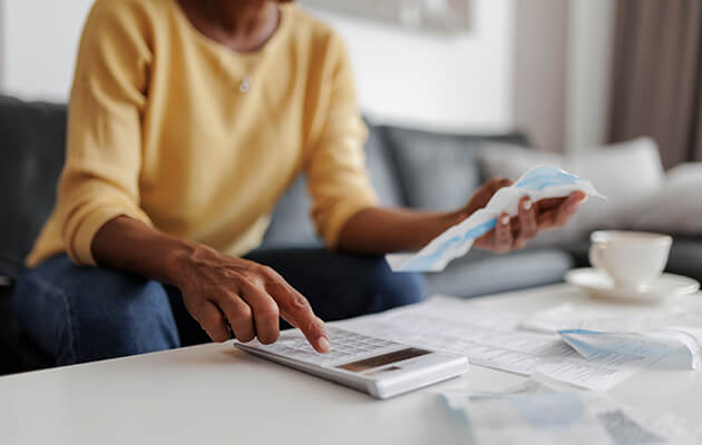 Large Women Using Calculator To Calculate Bills