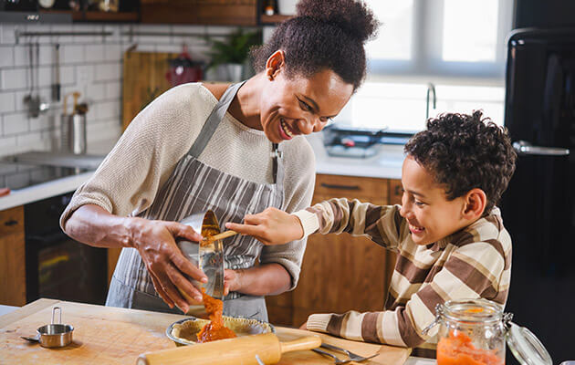 Large Mother Teaching Son Cooking In The Kitchen