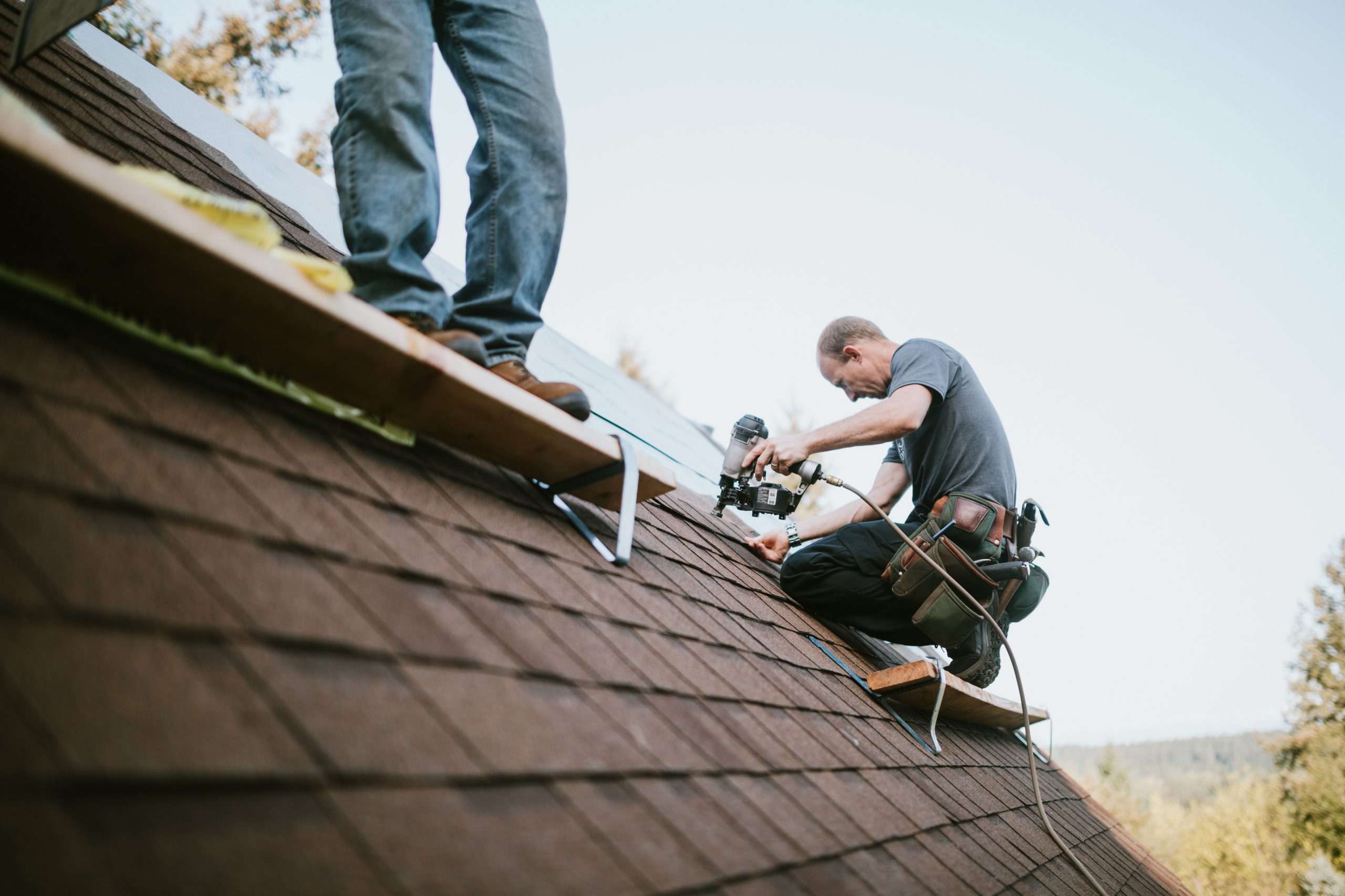 man installing shingles on roof repair hero