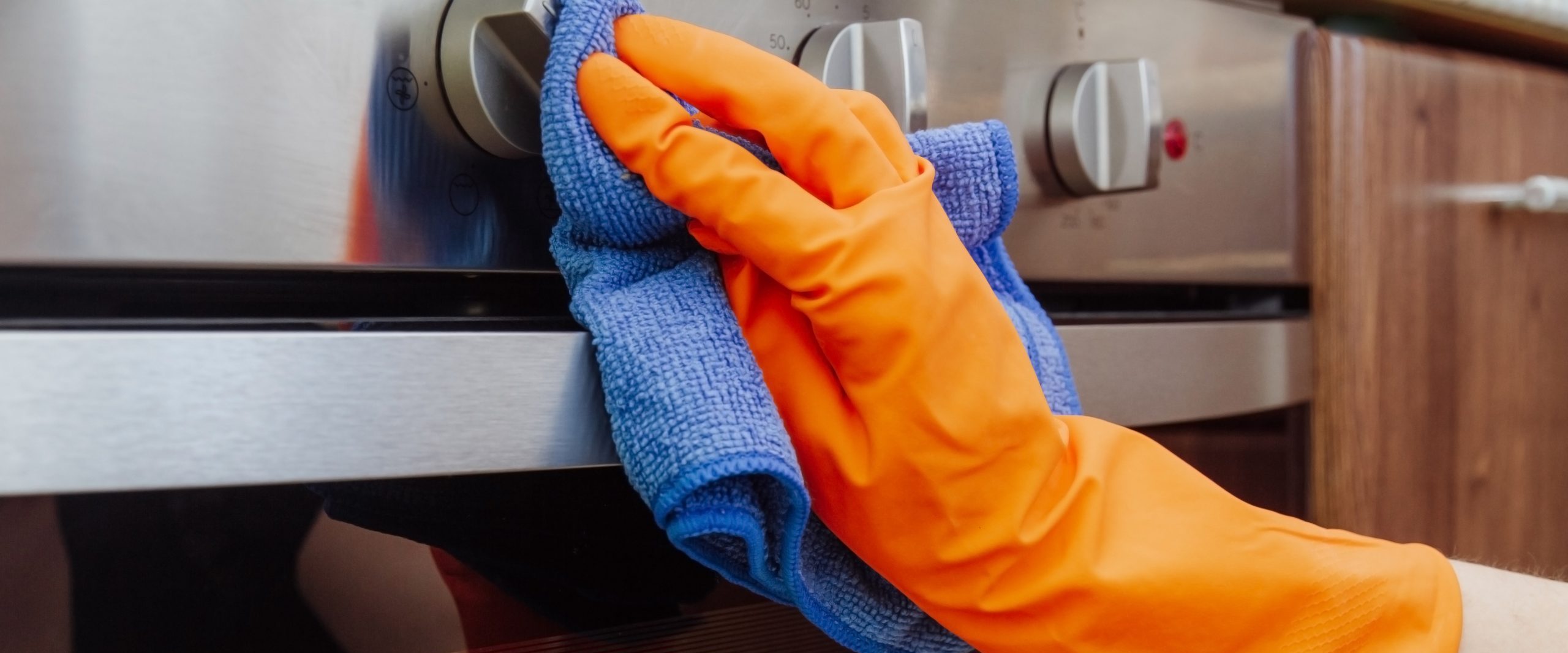 Hand with a microfiber cloth is being wiped on the outside of the electric oven.