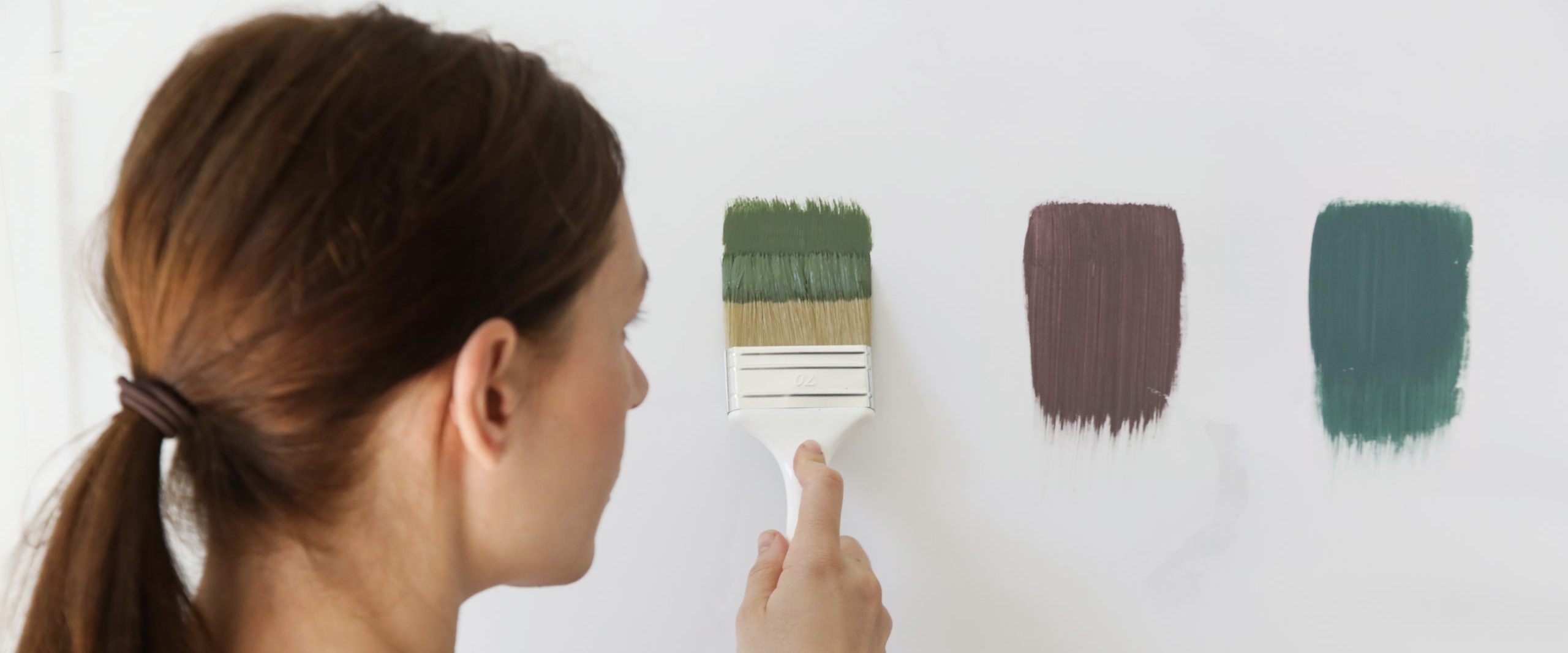 Woman is painting the wall with different color swatches. Process of choosing the right color for the wall, DIY home improvement concept. Category People