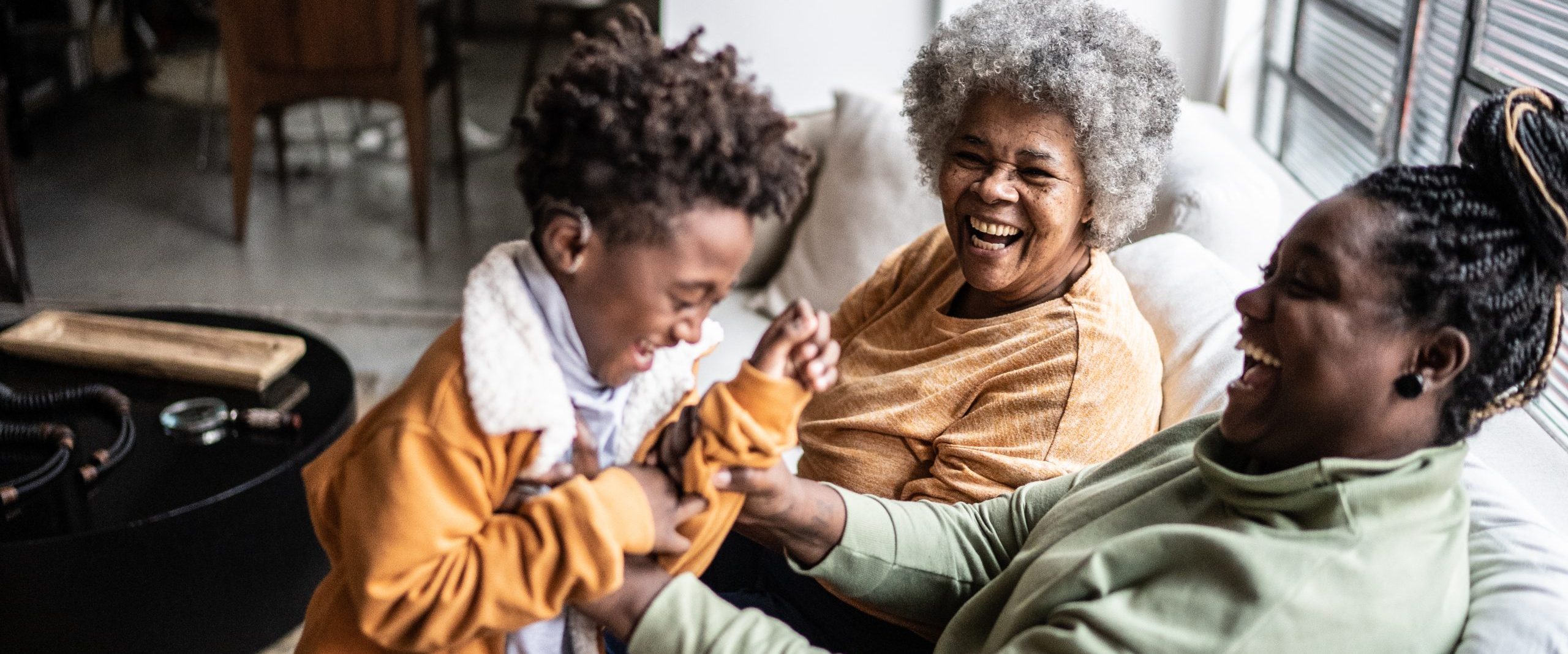 Child playing with his mother and grandmother in the living room at home