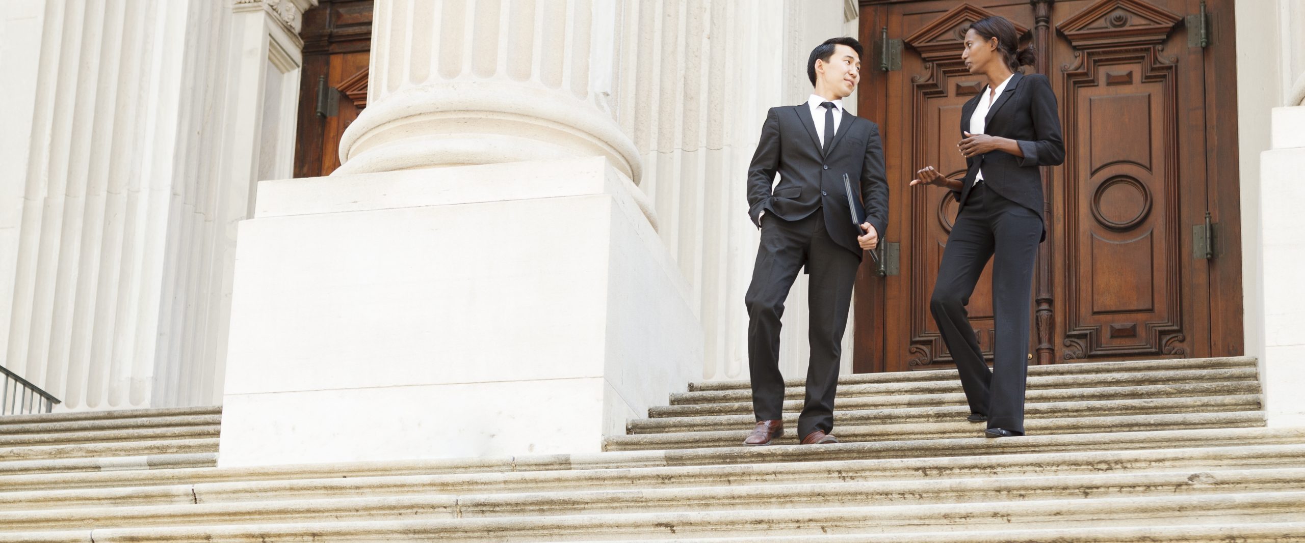 Well Dressed Man and Woman Descend Courthouse Steps in Conversation