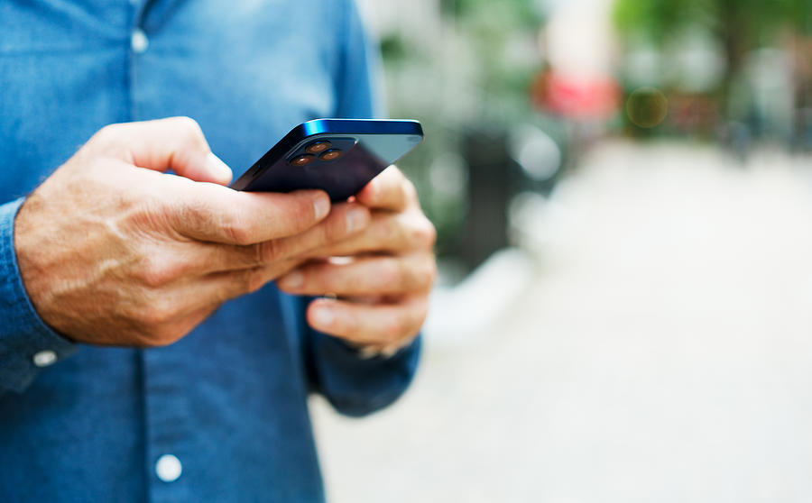 A man in a blue shirt reviews information on his cell phone