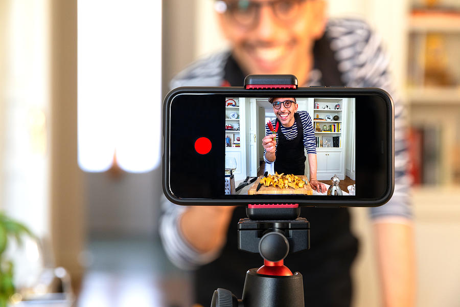 A man shows his ingredients to his phone, livestreaming his cooking.