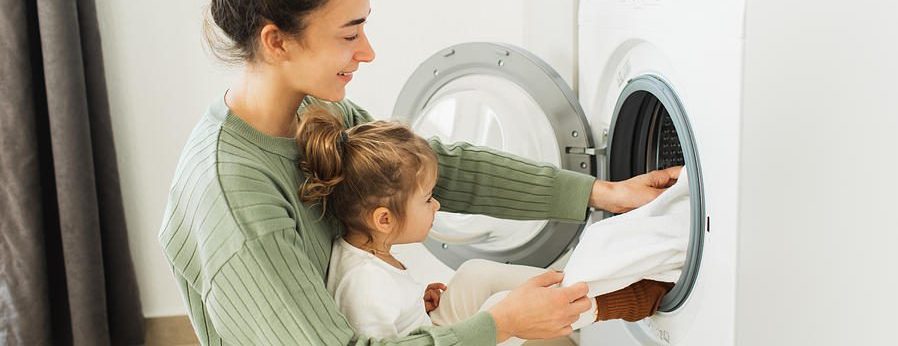 Young mother and small daughter unload the dryer together