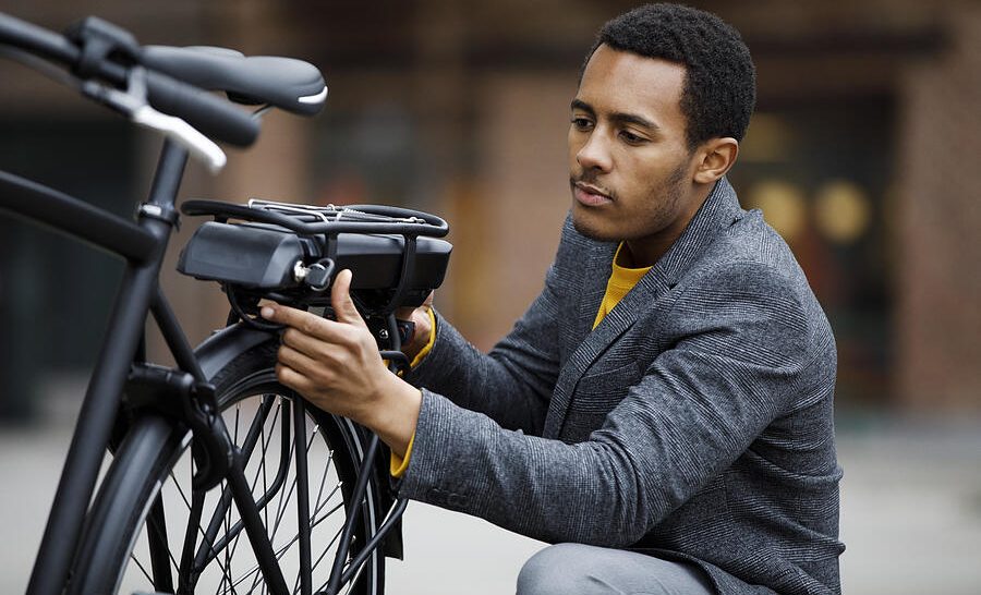 A man adjusts his electric bike battery pack during the day.