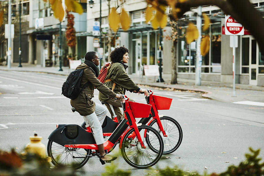 Two women commute on electric bikes in autumn