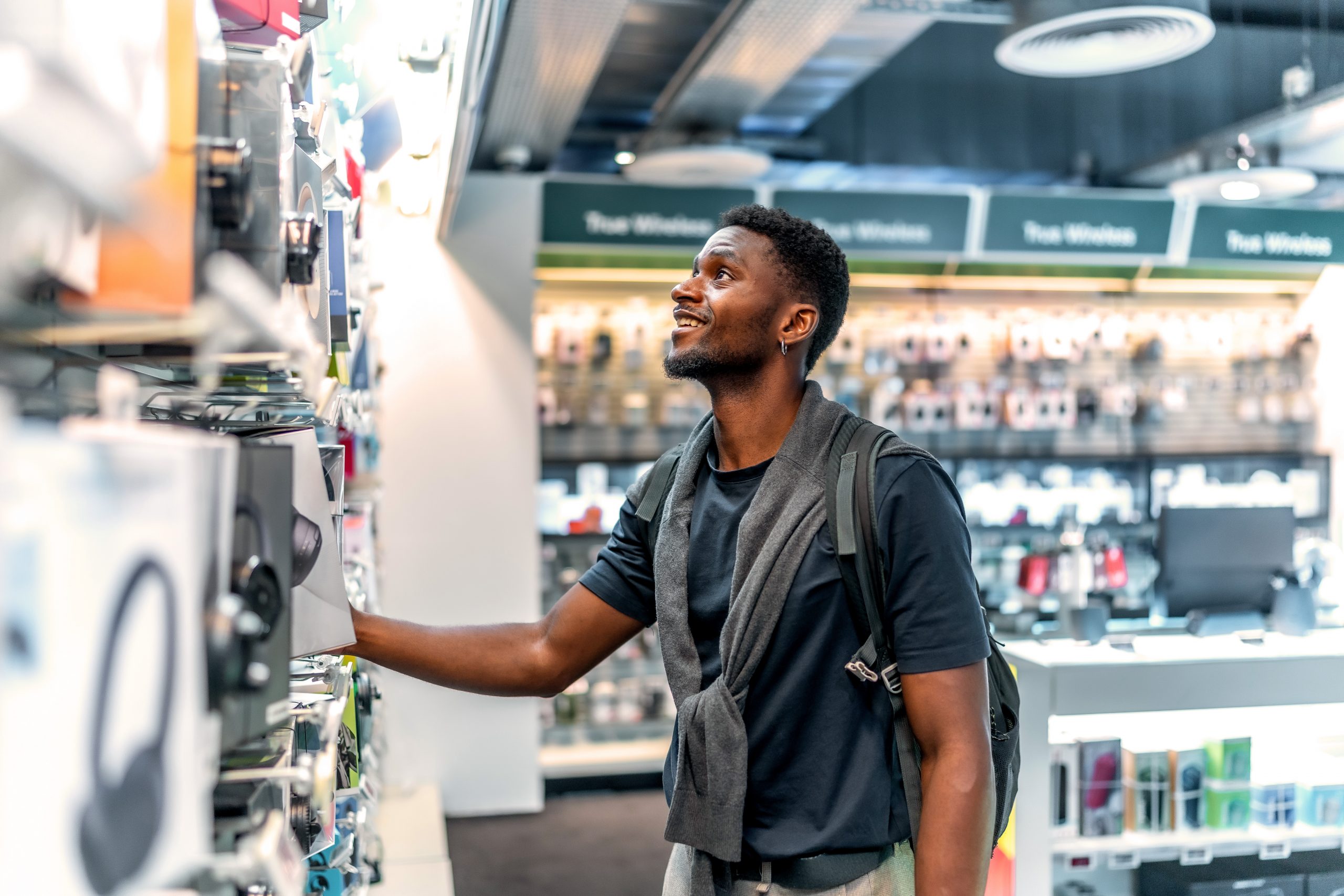 A male college student looks at speakers in an electronics shop.