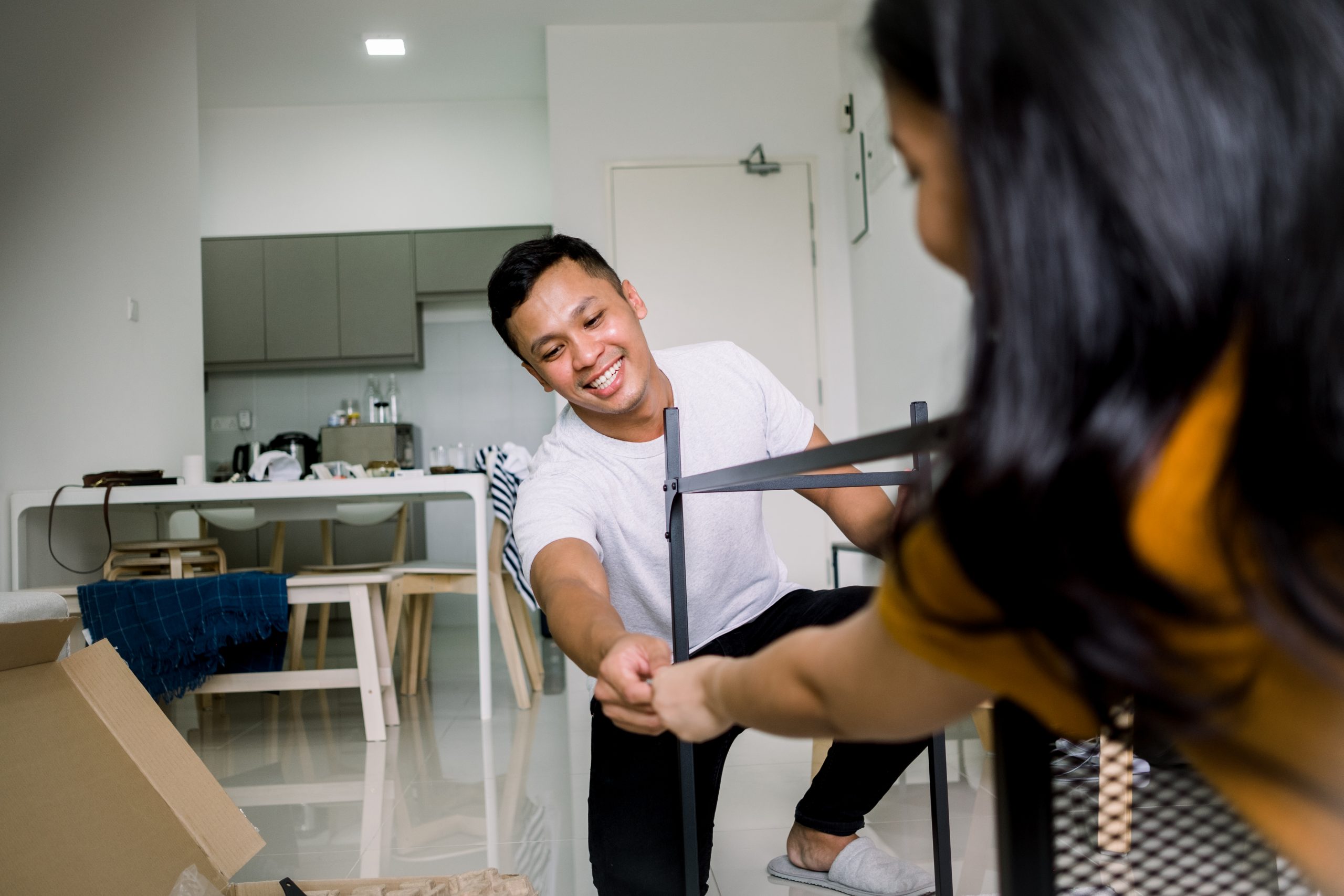 A couple in an apartment happily work together to build a desk.