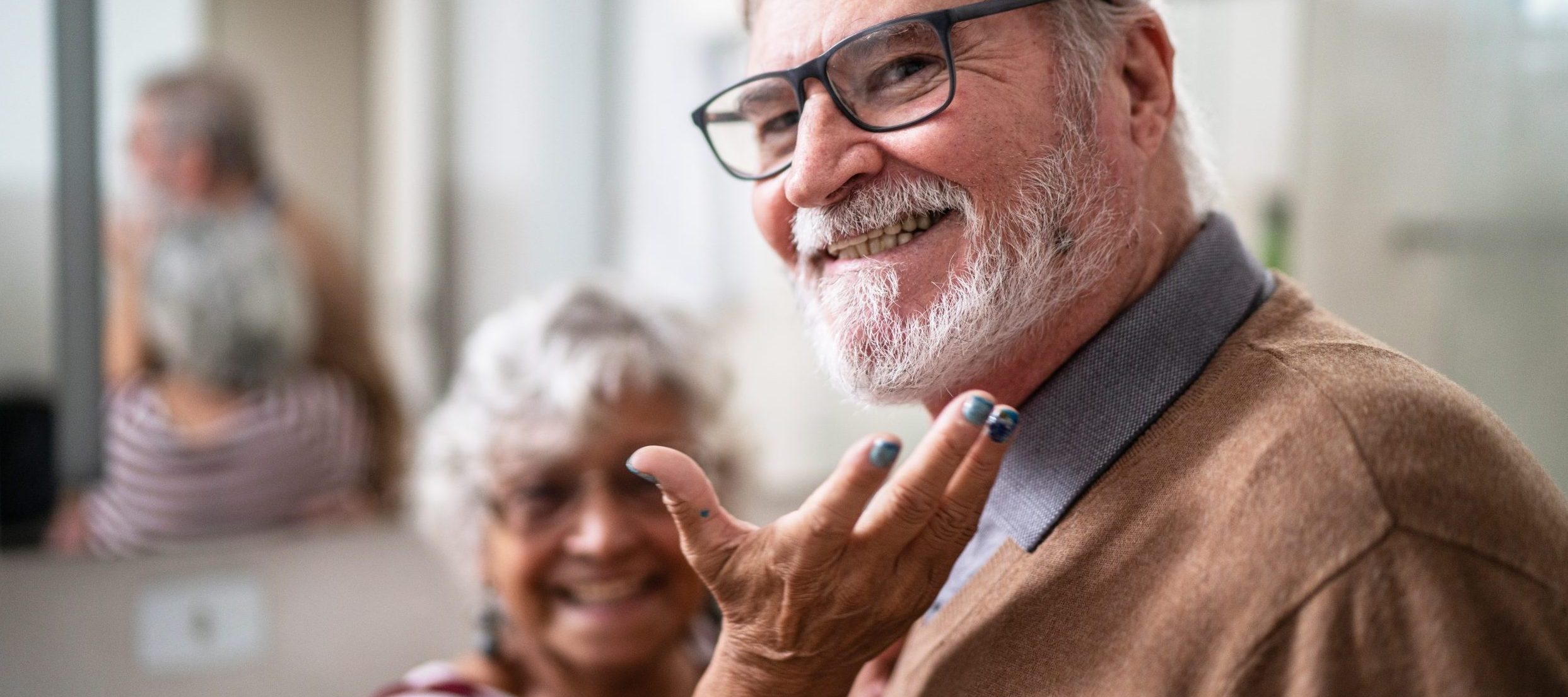 An older couple smiles at the camera, the wife showcasing her husband’s smile.