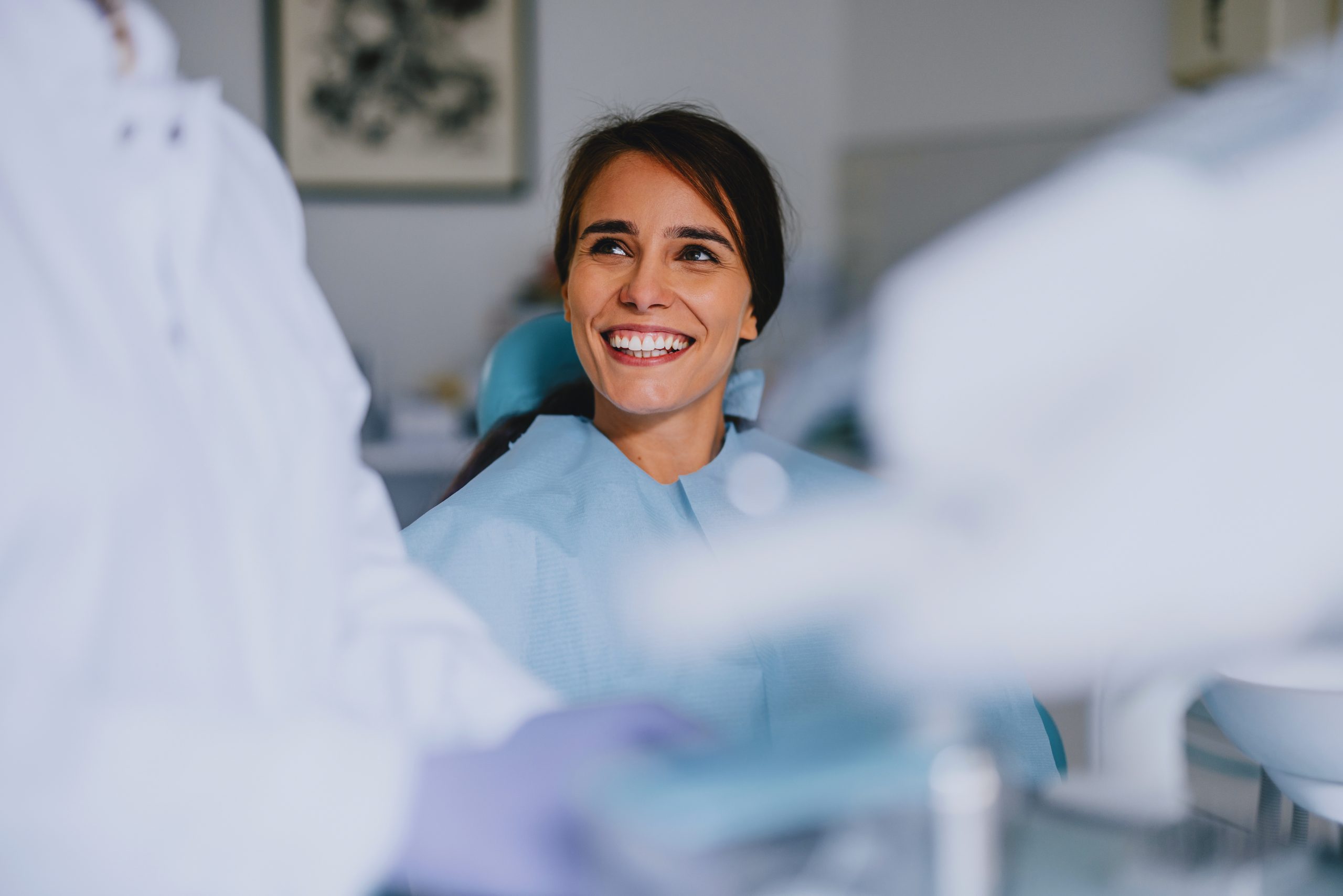 A woman smiles as she sits ready for her dental checkup.