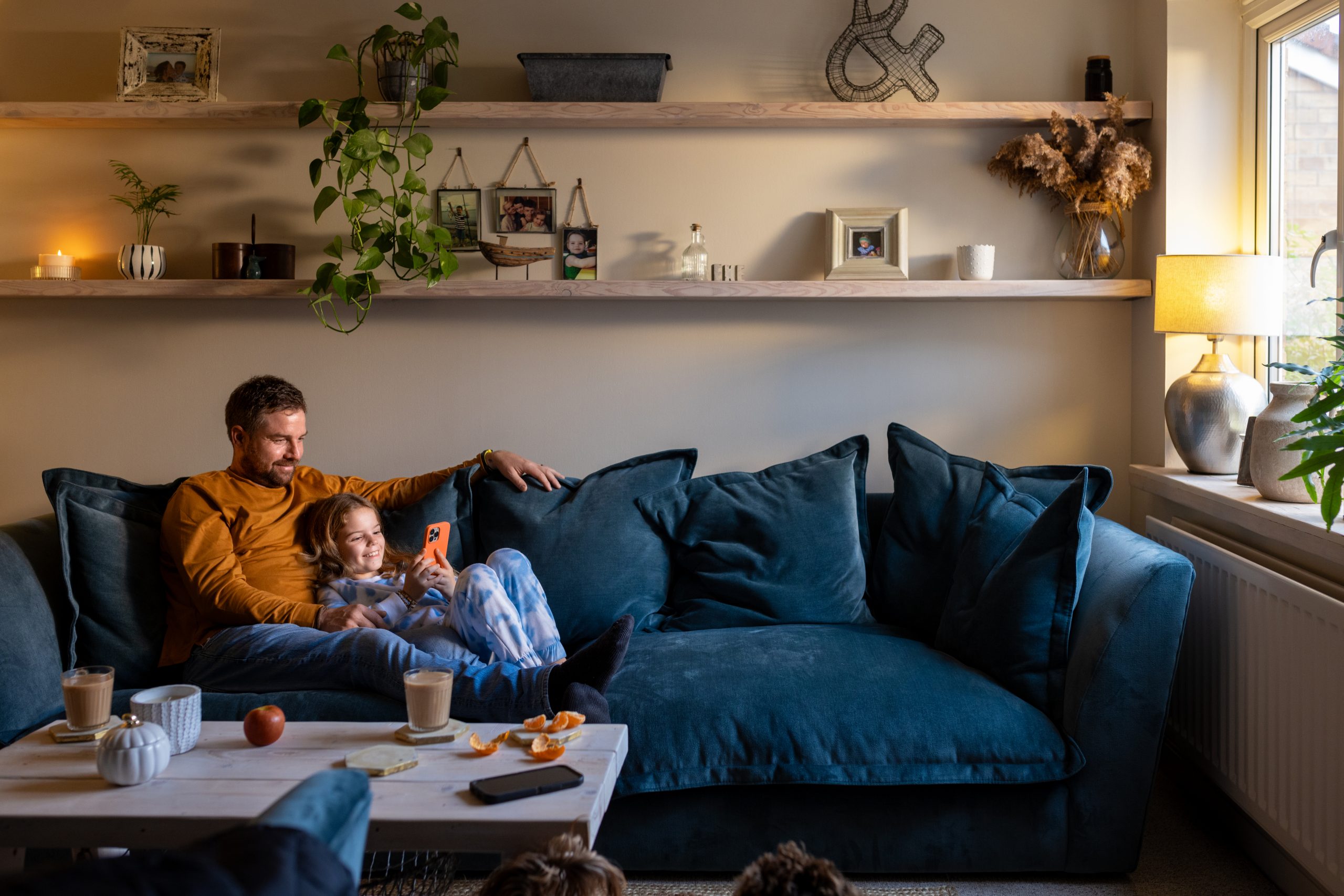 A dad and daughter sit on an oversized sofa.