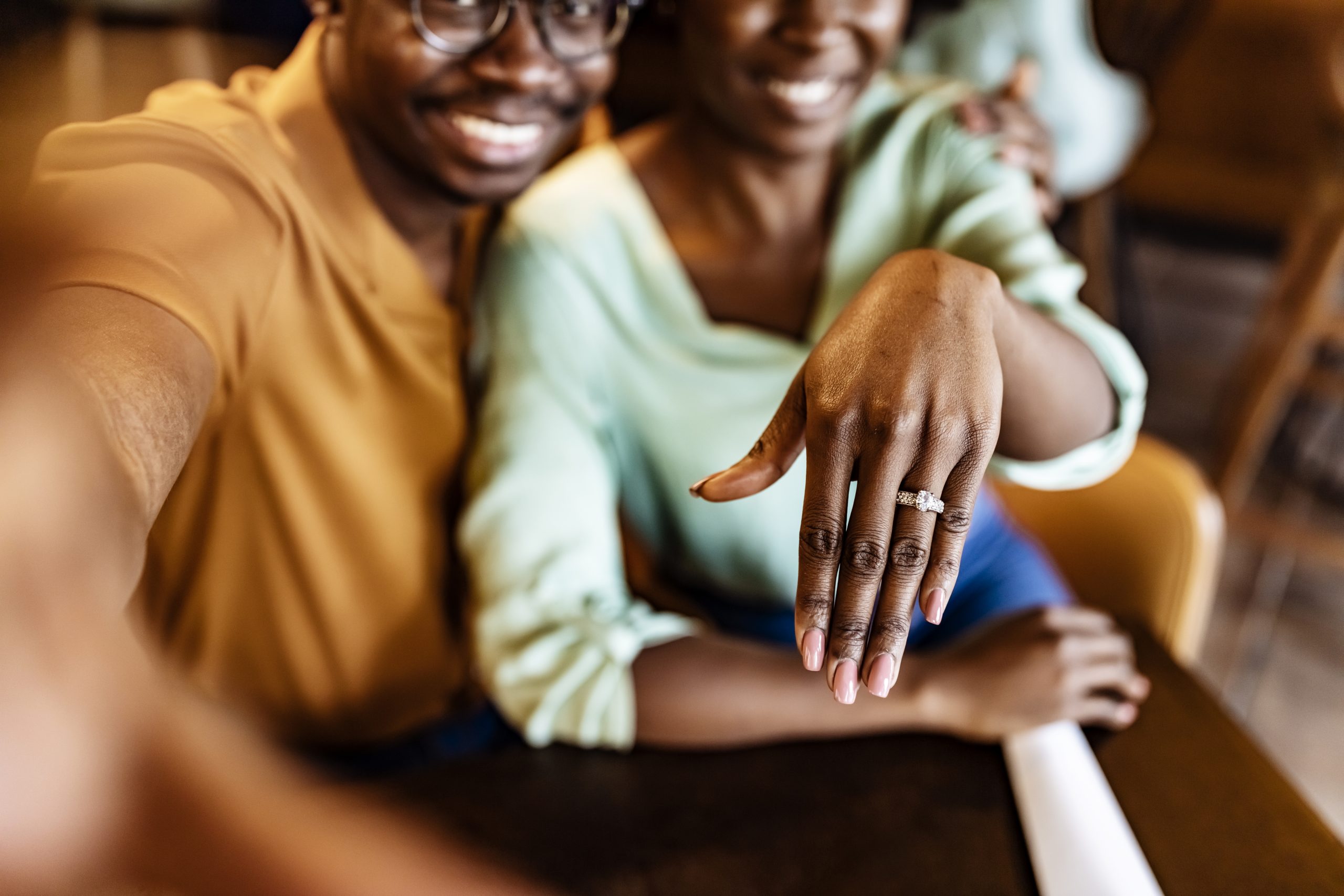 A recently engaged couple shows off the finance's diamond ring.