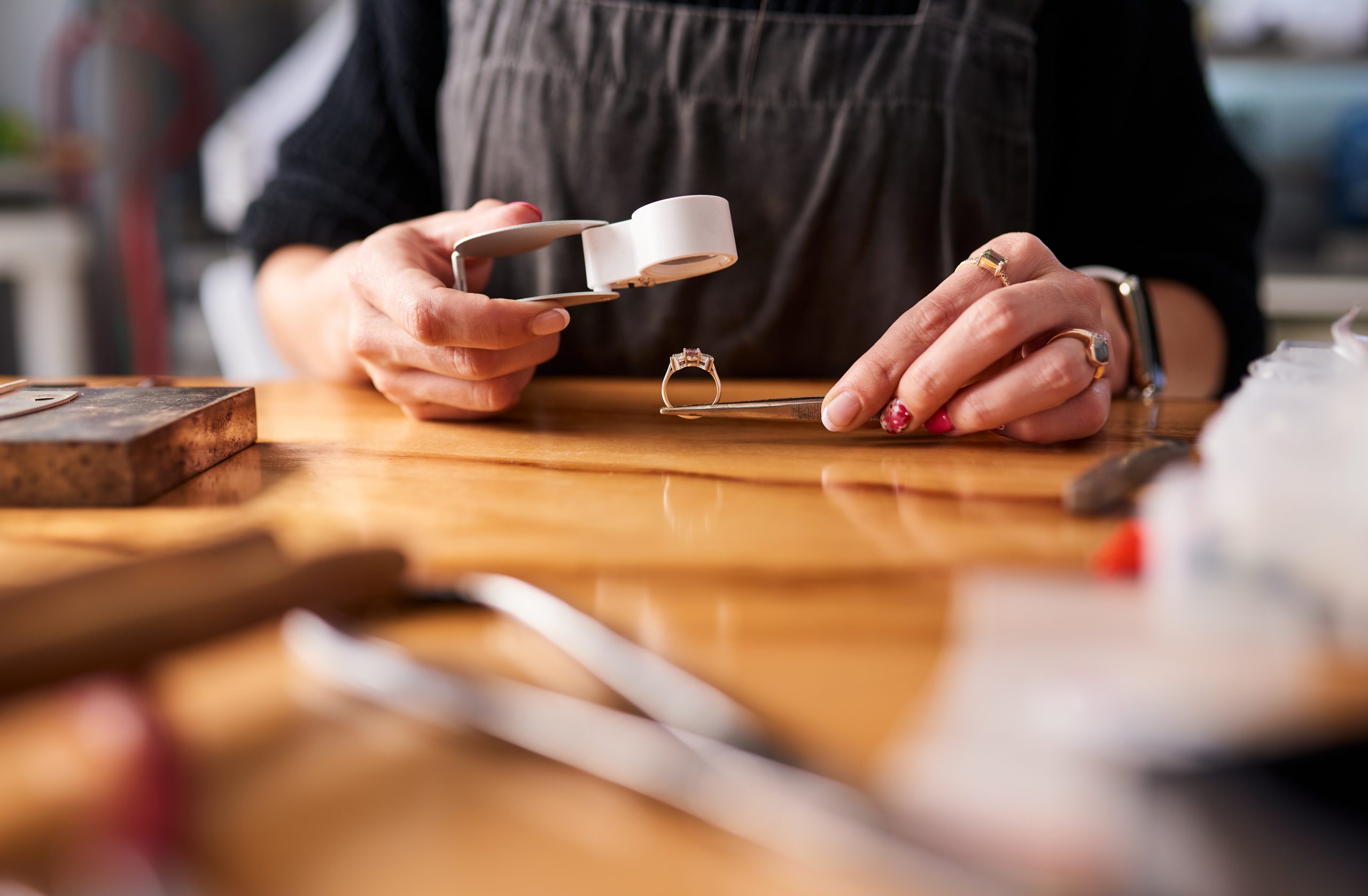 A jeweler studies the carats of a diamond ring with a magnifying glass.