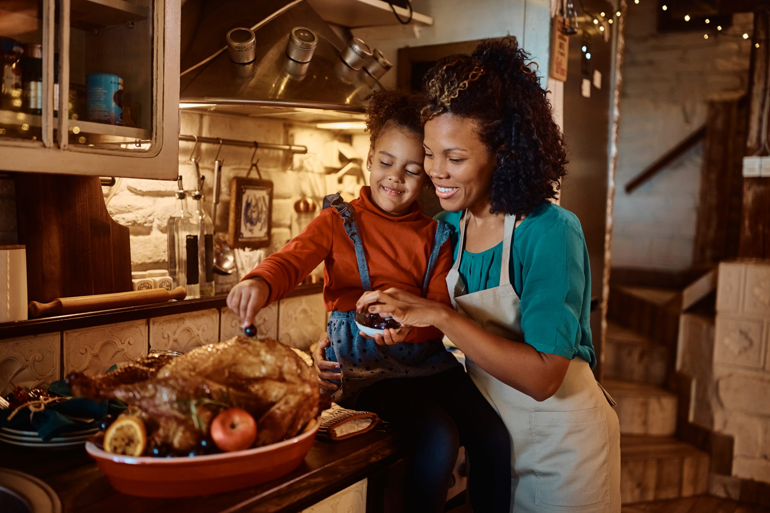 A mother and her daughter prep the turkey in the kitchen.