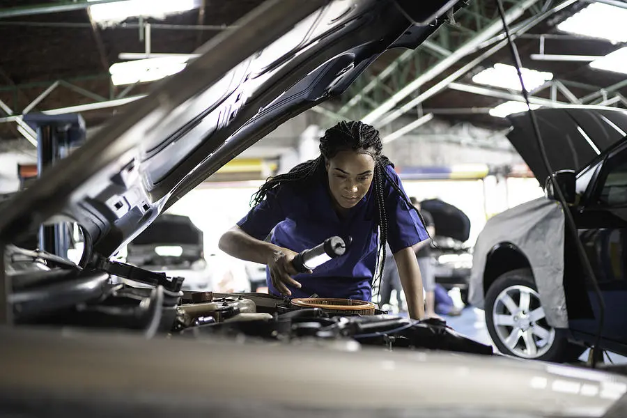 A mechanic assessing a vehicle inspection in an auto body shop.